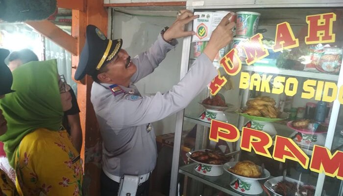 Kepala Terminal Kalideres, Revi Zulkarnaen memasang stiker di warung nasi pedagang di terminal setempat.