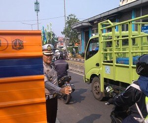 Petugas kepolisian saat tengah mengatur kendaraan yang terjebak macet di Jalan Otista. (Ifand)