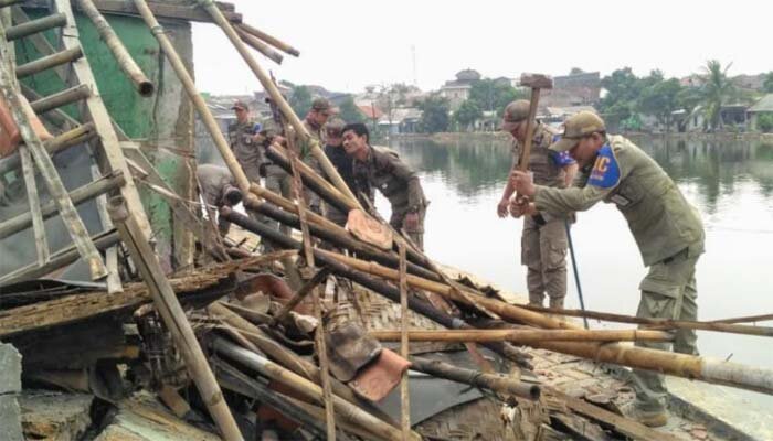 Sejumlah petugas Satpol PP Depok tengah membongkar puluhan warung dan lapak jualan di pinggir Situ Sawangan. (anton)