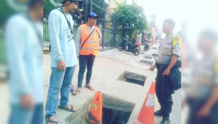 Anggota Bhabinkamtibmas Kemiri Muka Aiptu Rojjudin memeriksa pencurian penutup besi gorong-gorong di Jalan Margonda, supaya tidak membahayakan pengendara di kasih cone. (angga)