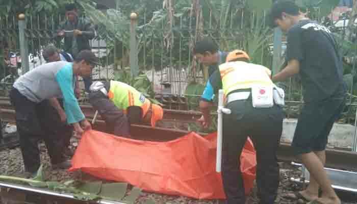 Petugas security Ka membantu petugas palang hitam mengevakuasi mayat dari pinggir rel yang tercecer anggota badannya. (Angga)