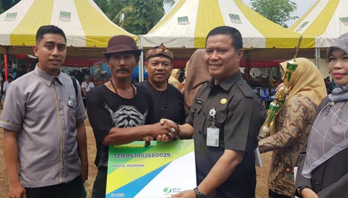 Asda I Kabupaten Bekasi Juadi, menyerahkan secara simbolis kartu kepesertaan pada penggali kubur.(ist)