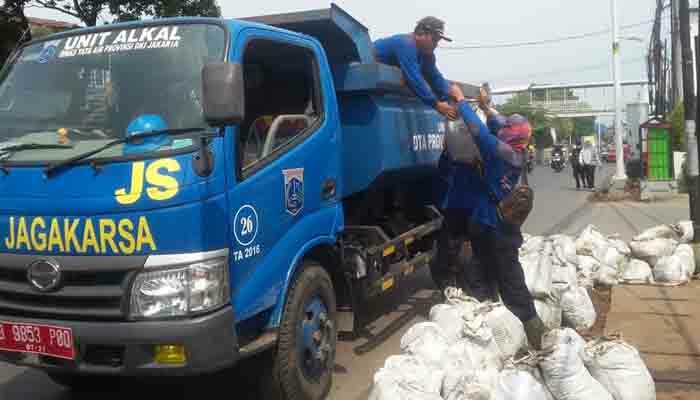 Sejumlah petugas sedang mengangkut karung berisi lumpur yang berada dari saluran air. (wandi)