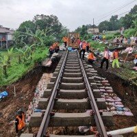 Para pekerja tengah memperbaiki jalur kereta yang terkena dampak longsor. (ist)