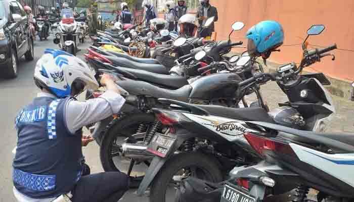 petugas sedang melakukan tindakan mengempesin ban motor yang parkir sembarangan. (wandi)