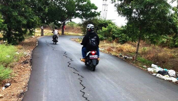 Pengendara sepeda motor melintasi jalan kabupaten yang retak. (taryani)