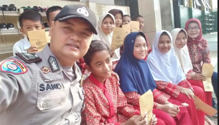 Anggota Bhabinkamtibmas Kelurahan/Kecamatan Cibadak, Brigadir Sandi Praja saat menyantuni anak yatim-piatu.(ist)